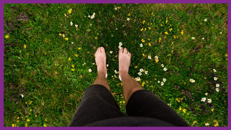 Someone stood barefoot on grass grounded to the floor.