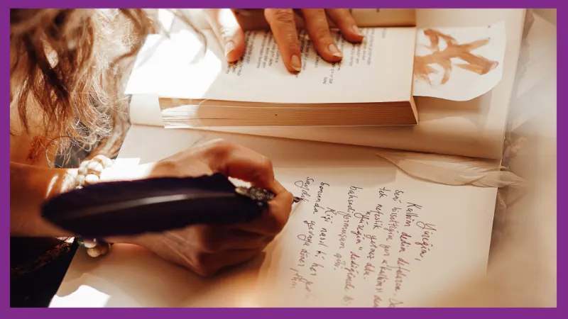 A close up of a woman writing in a journal with pen and ink.